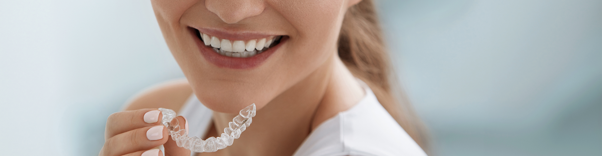 smiling woman placing clear aligner in her mouth